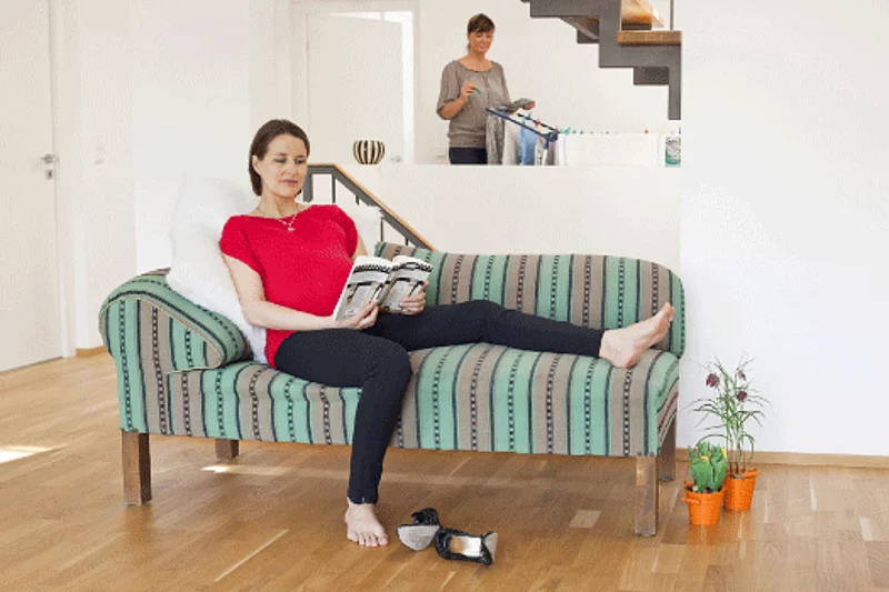 Schwangere Frau auf einem Sofa, die einen Buch liest